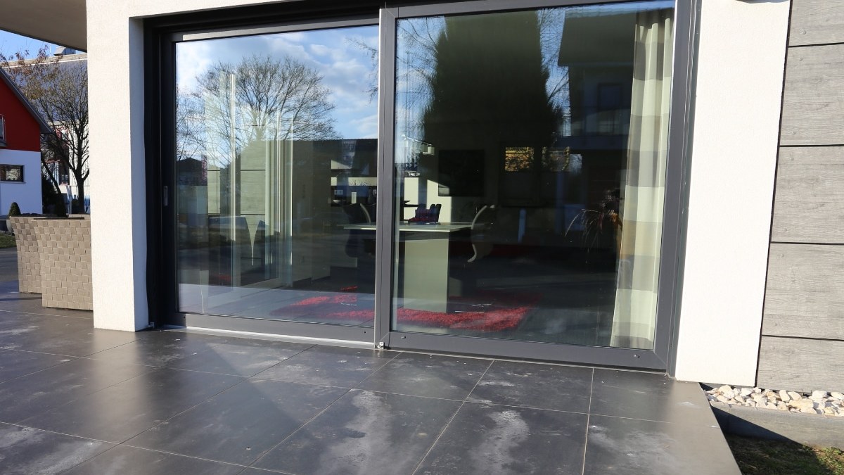 Moderne aluminium schuifpui met slanke antracietprofielen op strak terras, geplaatst door DEAA Kozijnen
